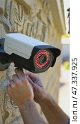 Security technician installing surveillance camera on stone wall. Стоковое AI-видео, аниматор Юрий Поздников / Фотобанк Лори