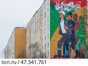 Город Тында, Амурская область, Россия. Вид на большое граффити на стене жилого дома, посвящённое строителям Байкало-Амурской магистрали (БАМ) и города Тынды. Красивый мурал с изображением молодых энергичных людей, идущих на стройку. (2024 год). Редакционное фото, фотограф Андрей Степанов / Фотобанк Лори