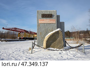 Памятник, посвящённый строителям Байкало-Амурской магистрали (БАМ). Город Северобайкальск, Республика Бурятия, Сибирь, Россия. На памятнике надписи: «1977» и «Слава первопроходцам БАМа». На дальнем плане путеукладчик-памятник (укладочный кран). Достопримечательности Северобайкальска. (2024 год). Редакционное фото, фотограф Андрей Степанов / Фотобанк Лори