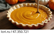 A delicious pumpkin pie filling is being mixed in a fluted crust, perfect for fall gatherings. Nearby, small orange and white pumpkins create a festive vibe. Стоковое AI-изображение, AI-художник Sergey Grishin / Фотобанк Лори