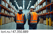 Two warehouse workers in safety vests and hard hats observe the storage area filled with boxes, ensuring smooth operations during a busy day. Стоковое AI-изображение, AI-художник Sergey Grishin / Фотобанк Лори
