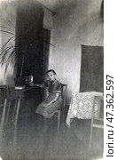 Пожилая женщина сидит в комнате за столом у горшка с цветком. Стоковое фото, фотограф Retro / Фотобанк Лори