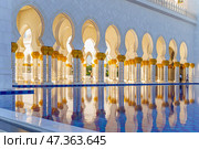 Abu Dhabi, United Arab Emirates - Jan 10 2024, panoramic view of Sheikh Zayed Grand Mosque colonnade with arches and pool on foreground, at daytime, Abu Dhabi, United Arab Emirates. Редакционное фото, фотограф Сергей Богомяко / Фотобанк Лори