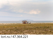 BAIKAL LAKE, KHUZHIR VILLAGE, IRKUTSK REGION, RUSSIA - August 01, 2024: Pribaikalsky Nature Park. A group of tourists have lunch in cozy wooden gazebo on shore of Small Sea on hot summer day. Редакционное фото, фотограф Виктория Катьянова / Фотобанк Лори