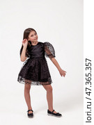 Elegant Young Girl in a Black Dress Posing Playfully in a Studio Setting. Стоковое фото, фотограф Aleksandr Golubev / Фотобанк Лори