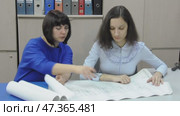 Woman in blue dress showing drawings to girl, office work. Стоковое видео, видеограф Катерина Белякина / Фотобанк Лори