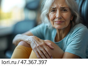 An elderly woman with grey hair and an expressive face that reflects traces of life, fatigue and, perhaps, pain. She sits, hugging her knees, in the shadows and semi-darkness, as if in moments of reflection or internal dialogue. Her gaze is directed straight into the lens - it is full of sadness, experiences and something unexpressed in words. Deep wrinkles on her forehead, compressed lips and a tense posture indicate internal tension, perhaps suffering or loneliness. This is the image of a woman who has experienced a lot, and now - in a moment of quiet but tangible pain. Стоковое AI-изображение, AI-художник Анна Кривицкая / Фотобанк Лори