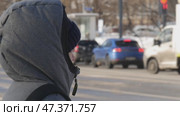 Человек в капюшоне стоит около дороги. Редакционное видео, видеограф Семён Прудий / Фотобанк Лори