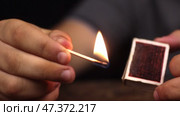 Крупный план: мужчина достает спичку из коробка и зажигает ее. Рука с горящей спичкой. Стоковое видео, видеограф Александр Собко / Фотобанк Лори
