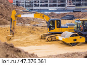 Heavy machinery for excavation and landscaping. Close-up view of an excavator and a road roller at a construction site. The excavator excavates the soil for excavation and construction. Стоковое фото, фотограф Photojuli / Фотобанк Лори