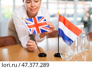 Blurry girl set midget flags of Netherlands and Great Britain before international negotiations. Стоковое фото, фотограф Яков Филимонов / Фотобанк Лори