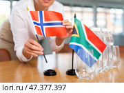 Blurry girl set midget flags of South Africa and Norway before international negotiations. Стоковое фото, фотограф Яков Филимонов / Фотобанк Лори
