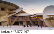 Doha, Qatar - Jan 06 2024, a panoramic view of National Museum of Qatar courtyard, patio, with some people in it, in shape of desert rose, at evening, Doha, Qatar. Редакционное фото, фотограф Сергей Богомяко / Фотобанк Лори