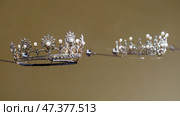 Doha, Qatar - Jan 06 2024, a close up view of historical vintage royal jewellery, the two crowns, exhibits of National Museum of Qatar, on monochrome background, under the glass, Doha, Qatar. Редакционное фото, фотограф Сергей Богомяко / Фотобанк Лори