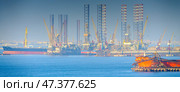 Manama, Bahrain- Jan 08 2024, Panoramic view of the industrial port buildings, constructions, cargo ship, tanker sailing in the foreground, the in the daytime, Manama, Bahrain. Редакционное фото, фотограф Сергей Богомяко / Фотобанк Лори