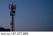 Мачта связи возвышается на фоне темнеющего неба, освещенная красными огнями. Стоковое AI-изображение, AI-художник Илья Старков / Фотобанк Лори