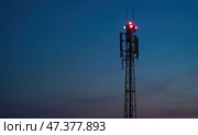 Мачта связи возвышается на фоне темнеющего неба, освещенная красными огнями. Стоковое фото, фотограф Илья Старков / Фотобанк Лори
