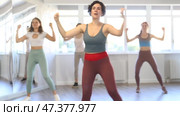 Expressive cheerful young Latina leading upbeat Zumba class for group of women in mirrored dance studio. Стоковое видео, видеограф Яков Филимонов / Фотобанк Лори