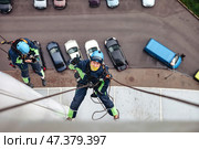 Industrial Mountaineers Perform Tasks High Above Urban Landscapes on a Building. Стоковое фото, фотограф Aleksandr Golubev / Фотобанк Лори