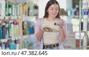 Selective young woman deciding which makeup items to buy in retail store. Стоковое видео, видеограф Яков Филимонов / Фотобанк Лори