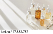 Beauty serums arranged on a light surface with gentle shadows in a serene indoor setting. Стоковое AI-изображение, AI-художник Сергей Толмачёв / Фотобанк Лори