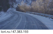 Snow-covered mountain road with icy patches and guardrail. Стоковое видео, видеограф Mariya Suranova / Фотобанк Лори