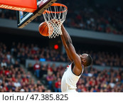 Basketball player is in mid-air, attempting to dunk the ball. Стоковое AI-изображение, AI-художник Sergey Grishin / Фотобанк Лори