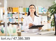 Middle-aged female pharmacist restocking with tablet in drugstore. Стоковое фото, фотограф Яков Филимонов / Фотобанк Лори