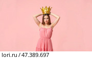 Female wearing elegant pink outfit, holding oversized golden crown, dull expression, ironic royal theme, comedy satire, modern princess, confident pose, casual background, fun personality. Стоковое AI-изображение, AI-художник Павел Муравьев / Фотобанк Лори
