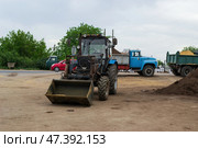 Колёсный трактор мтз82 беларусь, погрузчик, на территории сельскохозяйственного дачного кооператива. Волгоград, Городищенский район, Россия. (2024 год). Редакционное фото, фотограф Андрей Цыганков / Фотобанк Лори