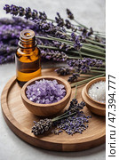 Lavender essential oil and salts displayed with fresh lavender sprigs on wooden plate during a serene afternoon setting. Стоковое AI-изображение, AI-художник Сергей Толмачёв / Фотобанк Лори