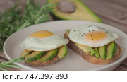 Fried Yolk eggs Two Toasts avocado, rosemary, seed. 4K Preparing healthy toast breakfast sandwich avocado slices rye wholegrain bread sunny side up egg on top. Healthy breakfast for two, couple. Стоковое видео, видеограф Елизавета Малкова / Фотобанк Лори
