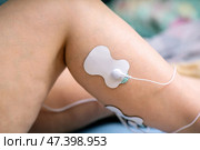Electrodes of muscle stimulator attached to woman's leg during EMS workout for toning and rehabilitation therapy. Стоковое фото, фотограф Татьяна Степанищева / Фотобанк Лори