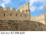 Historic stone fortification walls are under a vivid blue sky with clouds. Baku. Стоковое фото, фотограф EugeneSergeev / Фотобанк Лори