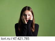 Teen Girl Expresses Surprise in a Studio With Green Background During a Creative Shoot. Стоковое фото, фотограф Aleksandr Golubev / Фотобанк Лори