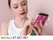 Woman musician holding ukulele and tuning its strings before she starts to play musical instrument. Стоковое фото, фотограф А. А. Пирагис / Фотобанк Лори