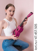 Young woman musician holding ukulele. Her face conveys joy, she looking at camera with sincere smile. Стоковое фото, фотограф А. А. Пирагис / Фотобанк Лори
