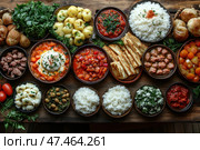 A richly served table with a variety of dishes laid out in ceramic bowls and plates. The food is presented in a traditional style and most likely belongs to Caucasian, Middle Eastern or Eastern European cuisine. Here you can see rice, stewed vegetables, meatballs, sauces, pickles, greens, flatbreads, potatoes, legumes and cheese dishes. The color palette is rich, with a predominance of warm and natural tones. The scene looks very appetizing, cozy and ideal for the theme of hospitality, family feasts, restaurants and ethnic cuisine. Стоковое AI-изображение, AI-художник Анна Кривицкая / Фотобанк Лори