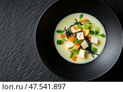 A top-down view of miso soup in a matte black bowl highlights its warm, golden broth. The elegant presentation enhances its traditional Japanese umami-rich flavor. Стоковое AI-изображение, AI-художник Nart / Фотобанк Лори