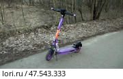 Электросамокат стоит на дорожке в лесу. Март. An electric scooter stands on a path in the forest. March. Редакционное видео, видеограф Горшков Александр / Фотобанк Лори