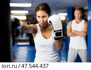 Asian woman in boxing gloves practicing punches on punchbag in gym. Стоковое фото, фотограф Яков Филимонов / Фотобанк Лори