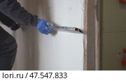 A male plasterer holds a metal ruler called a rule in his hands and aligns a newly plastered wall. Стоковое видео, видеограф Darya Komarova / Фотобанк Лори