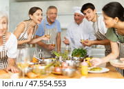 Positive attendees of cooking course talking cheerfully to each other in the kitchen. Стоковое фото, фотограф Яков Филимонов / Фотобанк Лори