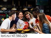 Excited diverse football supporters with flag of France watching tournament with beer and snacks in the pub. Стоковое фото, фотограф Яков Филимонов / Фотобанк Лори
