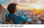 Person sits on a ledge, gazing at a stunning sunset while surrounded by a sprawling city landscape. The vibrant colors of the sky create a serene atmosphere, inviting moments of reflection. Стоковое AI-видео, аниматор Данила Большаков / Фотобанк Лори