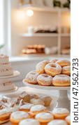 Delicious donuts and pastries displayed on cake stands, creating a sweet temptation in bakery. Стоковое AI-изображение, AI-художник Юрий Поздников / Фотобанк Лори