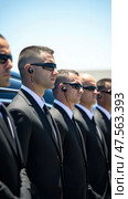 Security guards protecting important person, wearing suits and sunglasses. Стоковое AI-изображение, AI-художник Юрий Поздников / Фотобанк Лори