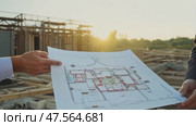 Workers assess construction blueprints on a building site during sunset, focusing on a detailed layout for their project. Стоковое AI-видео, аниматор Данила Большаков / Фотобанк Лори