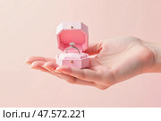 An elegant, voluminous hand holding an open box with a pink diamond ring is the epitome of a romantic marriage proposal. Стоковое AI-изображение, AI-художник ketpro.design / Фотобанк Лори