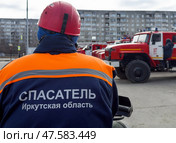 ANGARSK, IRKUTSK REGION, RUSSIA - April 08, 2025: On back of special clothing is inscription Rescuer Irkutsk Region against background of fire trucks lined up in row. Emergencies Ministry squad. Редакционное фото, фотограф Виктория Катьянова / Фотобанк Лори